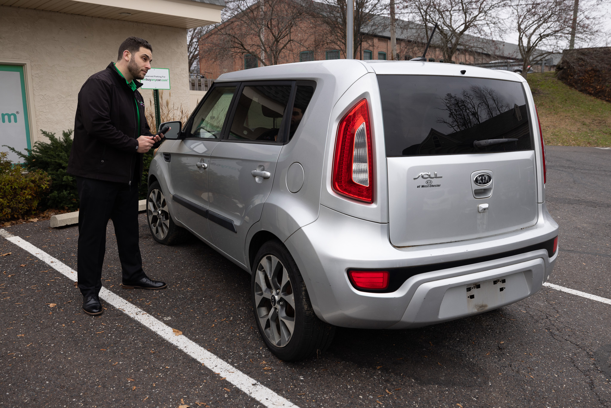 Car buyer checking the rear of a silver Kia Soul in a parking lot